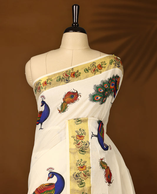 Elegant off white colour cotton Kerala saree with vibrant hand-painted peacock and feather motifs, accented by a floral printed golden border and pallu, paired with a matching blouse for a festive, graceful appeal.