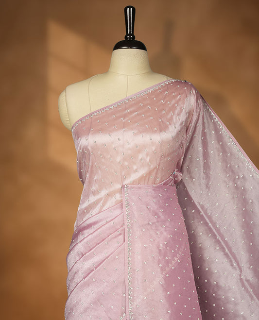 Pink colour net shimmer fancy saree adorned with scattered white stone buttas all over the body, paired with a delicate stone worked border and matching blouse.
