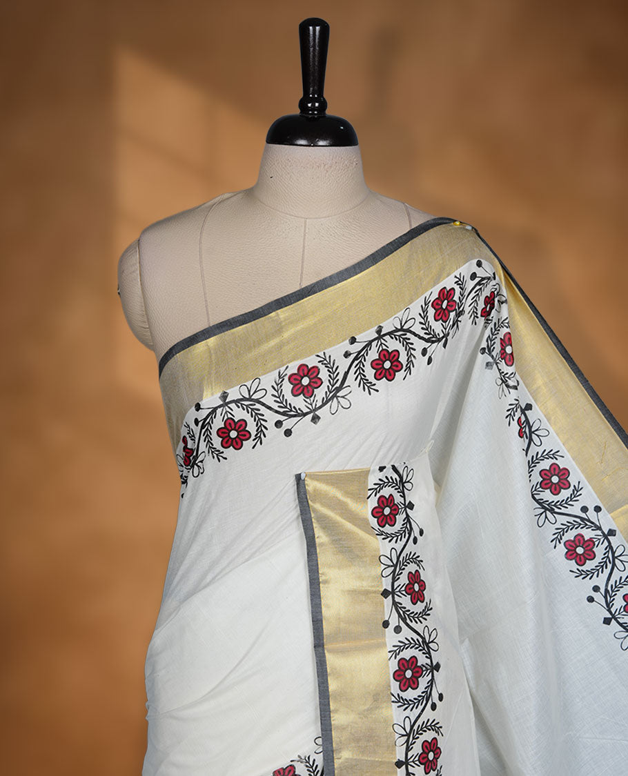 Off white colour cotton Kerala saree with floral printed borders, highlighted by a golden zari border and classic pallu, paired with a matching blouse.