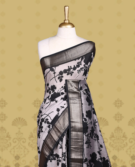 Grey colour saree adorned with bold black floral prints and a rich black zari border and stripped checkered pallu & Comes with a matching blouse piece.