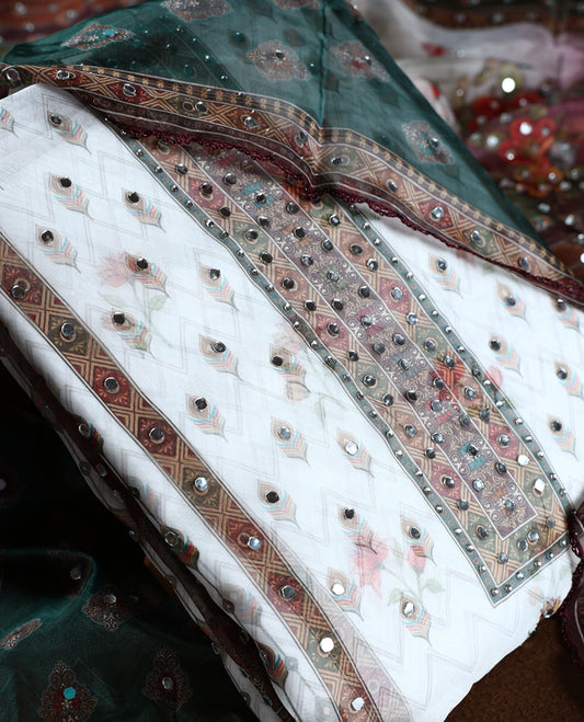 White colour churidhar material with mirror work and pastel floral prints, highlighted by earthy geometric borders & Comes with a plain white bottom and a dark green net dupatta adorned with shimmering mirror embellishments.
