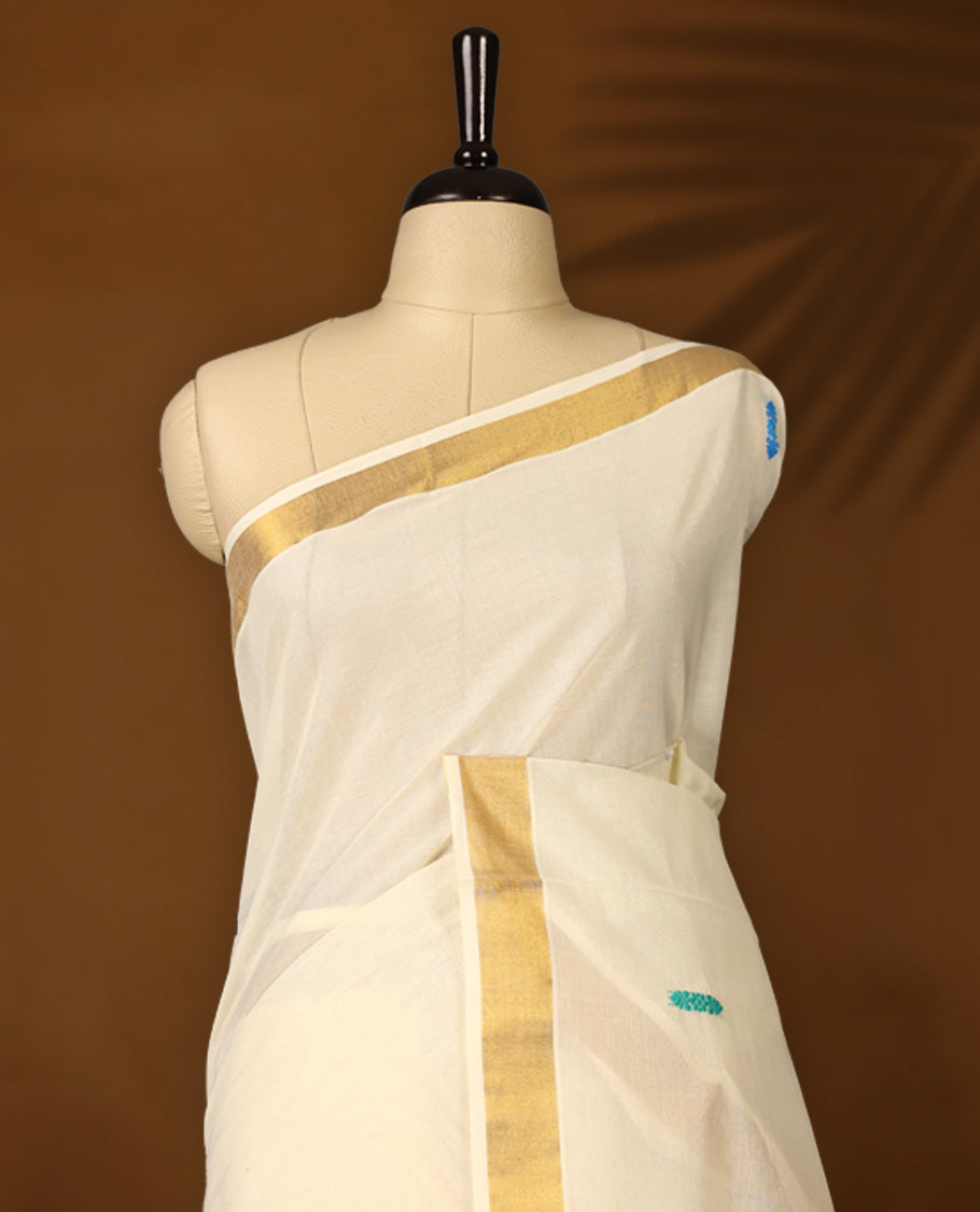 Elegant Off white colour cotton Kerala saree featuring colorful thread buttas and vibrant temple motifs on the pallu, finished with a classic golden zari border and paired with matching blouse.