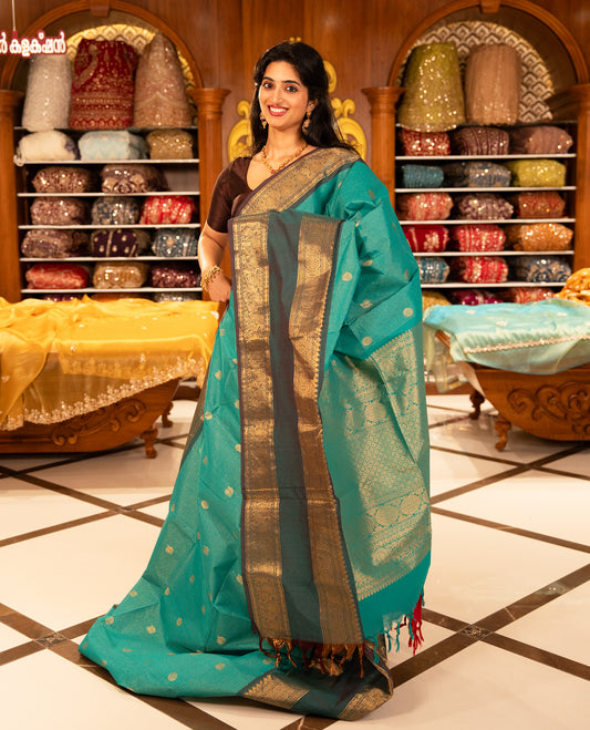 Aqua with Brown colour Chettinad cotton saree featuring Gold zari strips with peacock motifs on body, complemented by contrast colour border with zari design & grand pallu, comes with matching blouse piece.