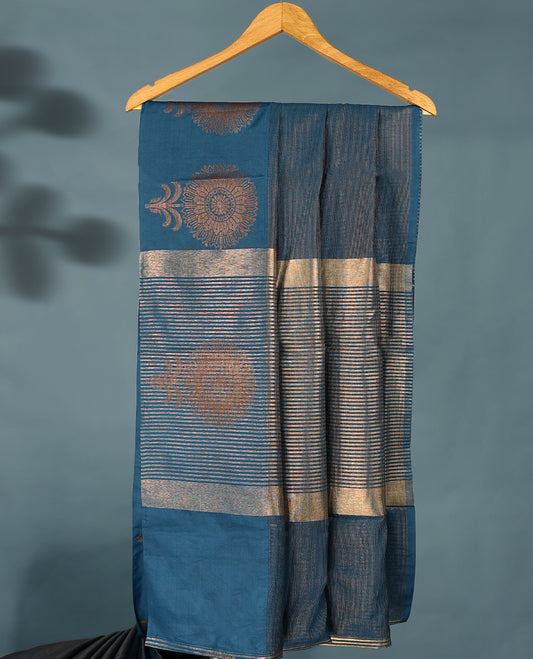 Blue Colour Semi Tussar Silk saree featuring golden zari horizontal lines across the body, adorned with bold floral motifs on the border, paired with a matching blouse.