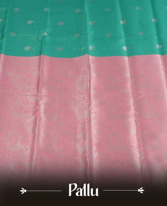 Aqua green colour semi silk saree adorned with subtle silver zari motifs on the body, complemented by a pastel pink pallu intricately woven with rich floral patterns border and pallu, and paired with a matching blouse
