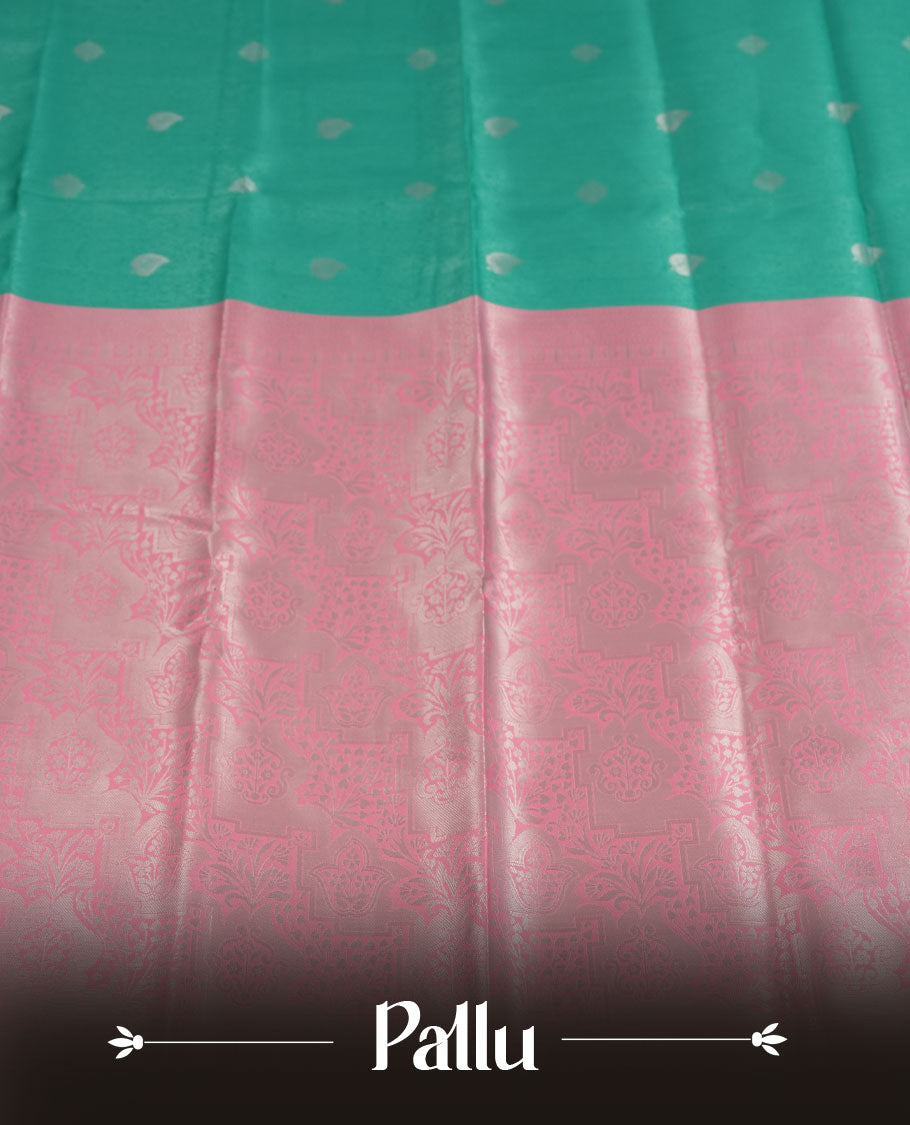 Aqua green colour semi silk saree adorned with subtle silver zari motifs on the body, complemented by a pastel pink pallu intricately woven with rich floral patterns border and pallu, and paired with a matching blouse