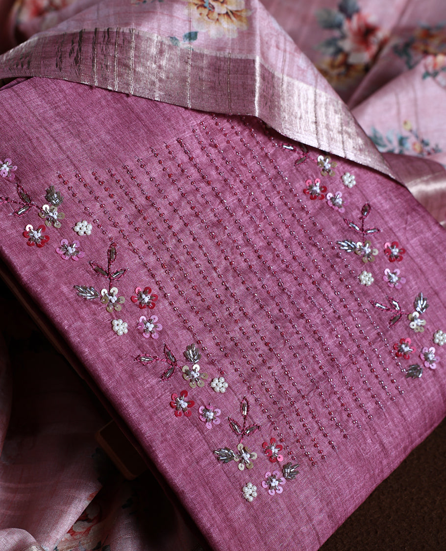 Onion pink colour churidhar material adorned with floral embroidery and sewn glass beads on the yoke, paired with a plain bottom and same colour dupatta featuring floral prints.