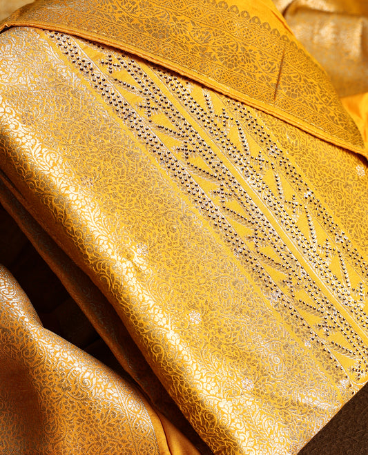 Yellow colour churidhar material with golden zari floral patterns and sparkling stone work, paired with a plain matching bottom and dupatta.