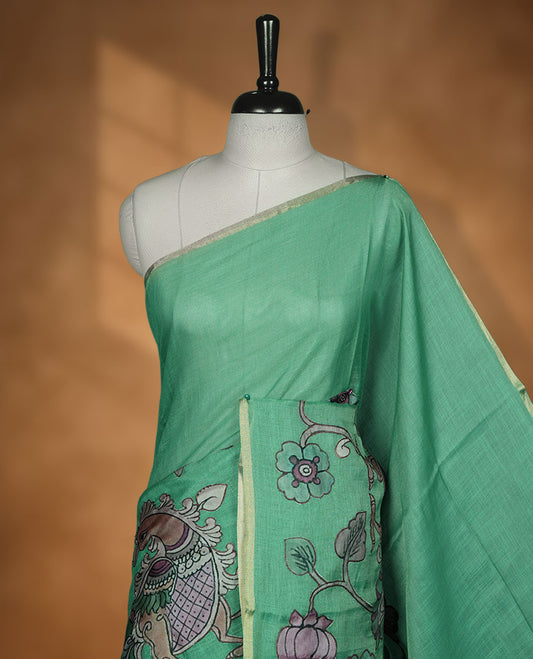 Mint green semi linen saree featuring hand painted floral and bird motifs across the pallu and border finished with subtle tassel detailing and paired with a matching floral print blouse