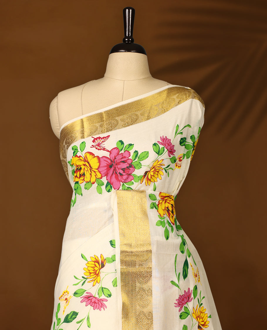 Elegant off white cotton Kerala saree adorned with hand painted floral motifs in pink, yellow, and green, beautifully accented by a rich golden zari border and pallu paired with matching blouse