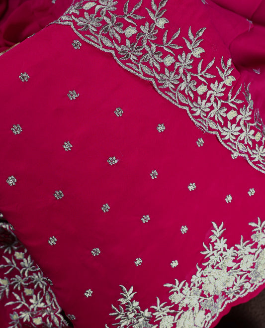 Pinkish red colour churidhar material adorned with elegant golden floral embroidery and delicate motifs, paired with a matching embroidered dupatta and plain bottom.