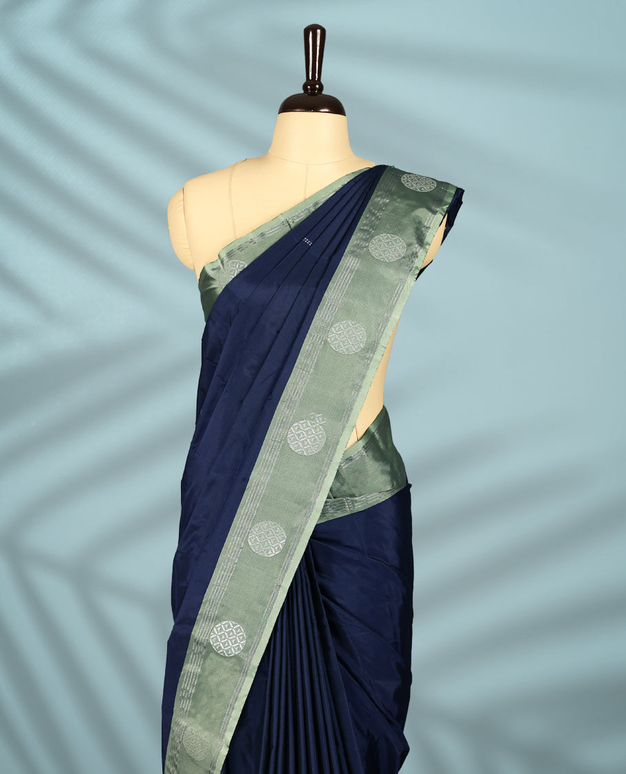 Navy blue Colour semi silk saree features Zari worked body enhanced by a pastel green zari border adorned with Silver circular motifs, and comes with a matching blouse.