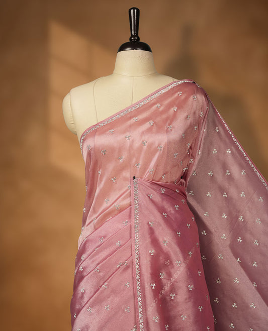Pastel Pink Colour net shimmer fancy saree adorned with scattered white stone buttas all over the body, paired with a delicate stone worked border and matching blouse featuring floral vine stone embroidery