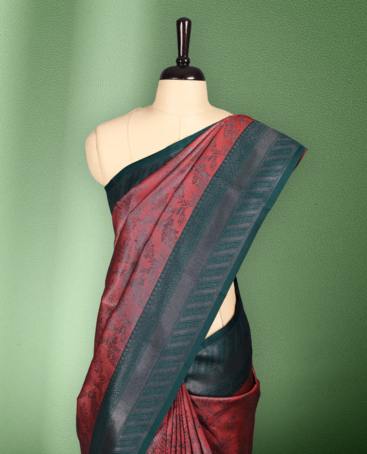 Brick Red colour semi silk saree featuring neem zari floral kodi motifs all over the body, complemented by a rich green woven border with geometric detailing, with matching blouse.
