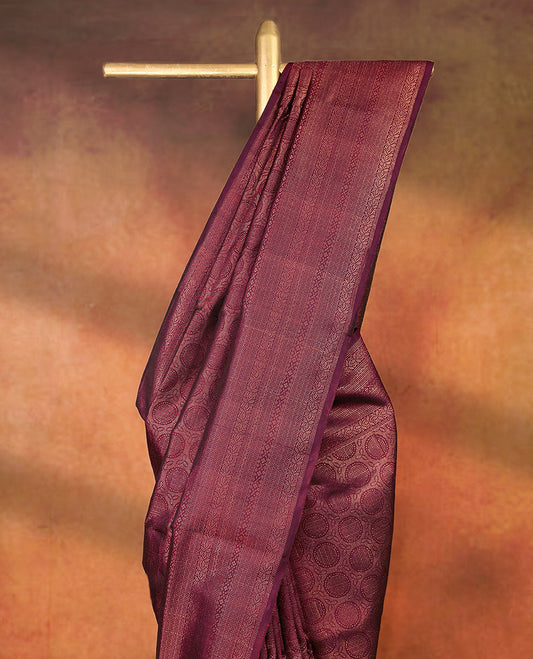 Deep Maroon colour pure Mayuri silk saree featuring finely woven Golden zari motifs across the body, detailed with a subtle geometric self border with intricate texture, with matching blouse