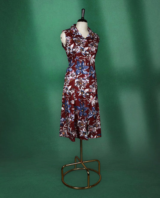 Maroon colour sleeveless dress featuring a collared neckline and button down front, adorned with bold blue and white floral prints a stylish and breathable choice for everyday elegance.