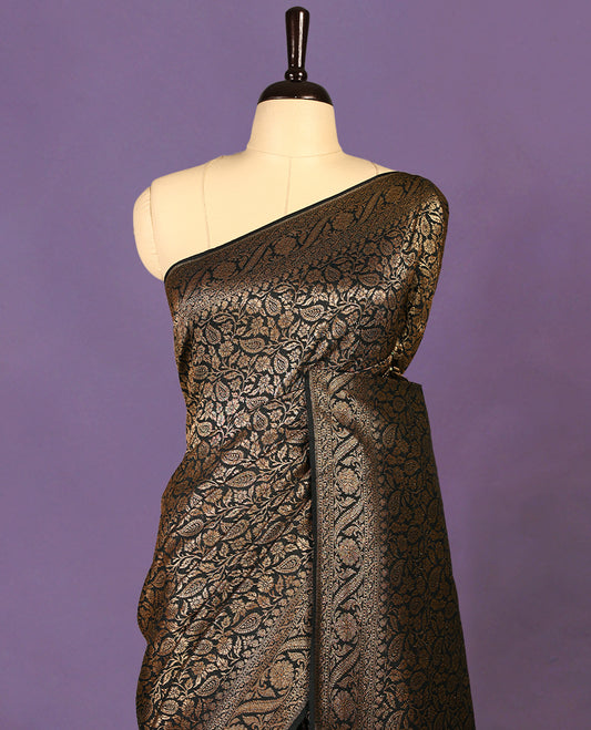 Black colour semi Banaras Katan silk saree featuring intricate Antique Bronze zari floral and vine patterns woven throughout the body, enhanced with a rich traditional border and detailed pallu, paired with a matching blouse piece.