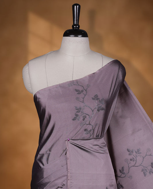 Pinkish gray colour semi soft silk saree adorned with delicate woven floral kodi motifs on the body, complemented by a Self colour woven pallu with intricate detailing and tassel accents without border & Comes with a matching blouse piece.