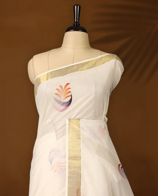 Elegant off white colour cotton Kerala saree with multicolor hand painted floral motifs on the pallu, scattered buttas on the body, and a golden zari border, blending traditional charm with artistic elegance.