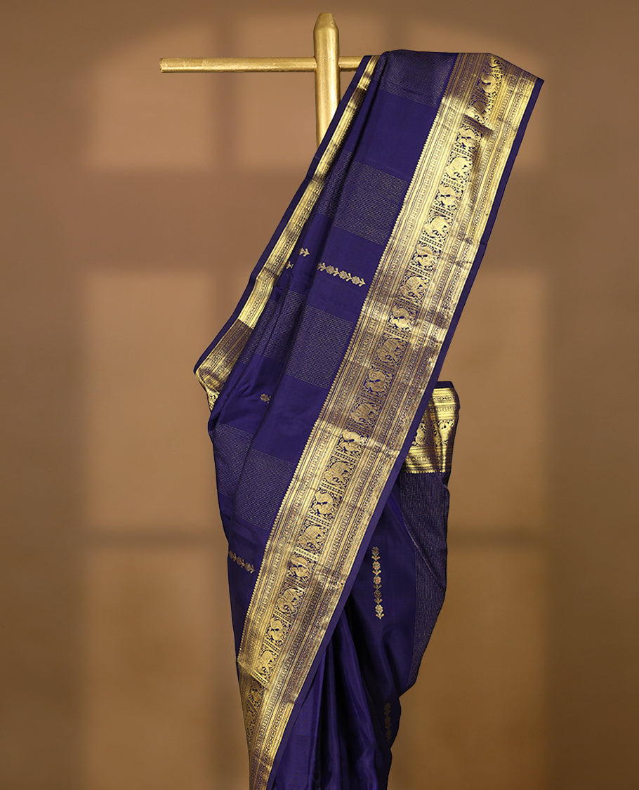 Navy blue Colour pure traditional Kancheepuram silk saree featuring antique zari line patterns on the body, complemented by a traditional border adorned with peacock and elephant motifs, and paired with a matching blouse.