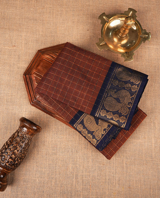 Brown colour sungudi cotton saree featuring gold zari check pattern across body, contrast Dark blue colour with gold zari peacock and floral pattern on border, without blouse piece.