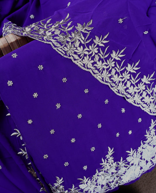 Indigo colour churidhar material adorned with silver floral embroidery and scattered butti work, complemented by a plain matching bottom and an elegant embroidered dupatta.