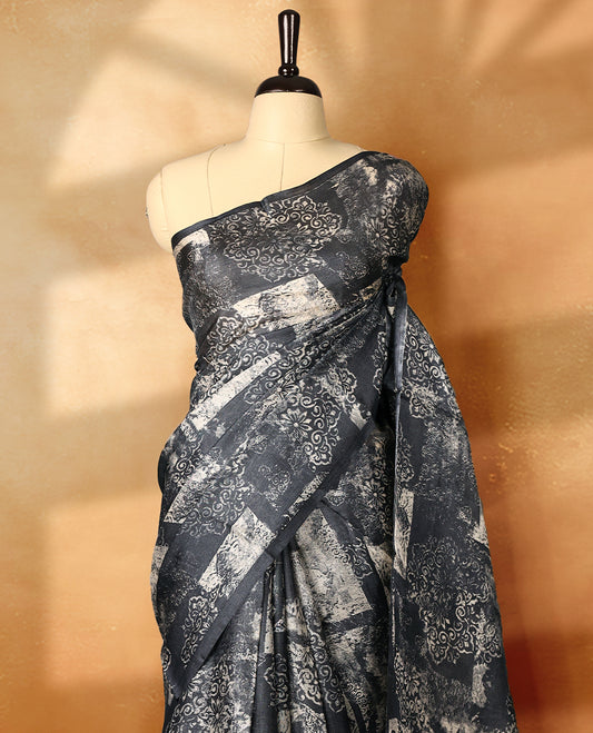 Black colour pure tussar silk light weight saree with full body abstract floral print, no defined border and pallu, paired with matching abstract printed blouse.