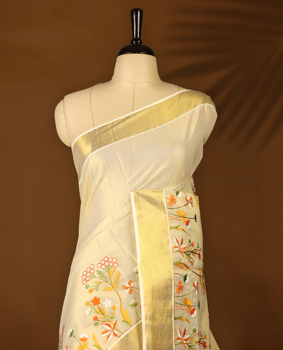 Light Gold colour Tissue Kerala saree featuring Orange and white Colour Floral thread work on body and a beautifully woven Gold Kasavu border, paired with a matching blouse perfect for festive occasions.