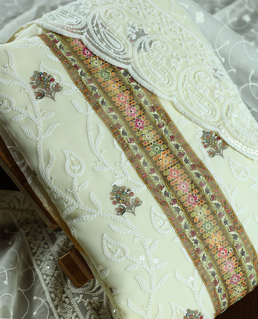 Cream colour churidhar material with heavy embroidered neck work, delicate floral motifs on the body, and multicolor panel detailing & Comes with matching plain bottom and embroidered net dupatta.