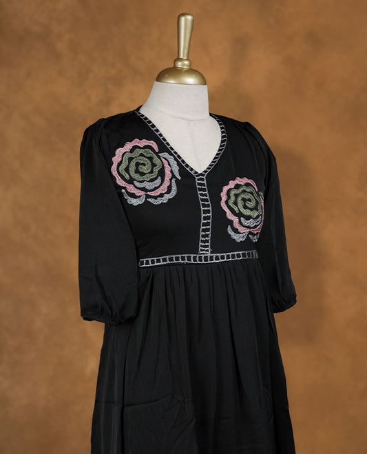 Black knee-length A-line dress with V-neckline, pastel spiral floral embroidery on yoke and hem, and elbow-length gathered sleeves.