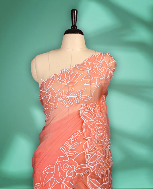 Peach colour net organza exclusive designer saree featuring a plain body and a beautifully adorned border with applique and thread embroidery work, complemented by a rich pallu and paired with a matching blouse