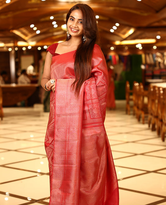 Cherry red colour pure Kancheepuram brocade silk saree featuring jaal and kodi design in a square pattern on the body, brocade border with zigzag detailing, antique gold zari rich pallu, paired with a matte finished blouse.