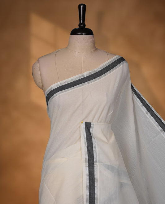 Off-white colour cotton Kerala saree with a subtle silver and black kasavu border, featuring a clean plain body, paired with a matching blouse.