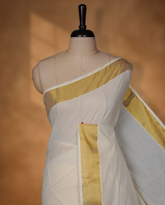 Off-white colour cotton Kerala saree crafted in a soft, sheer weave, finished with a classic rich gold kasavu border along the body and pallu, and paired with a matching blouse.
