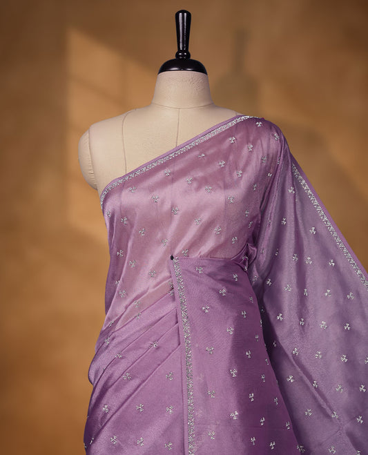 Lavender Colour net shimmer fancy saree adorned with scattered white stone buttas all over the body, paired with a delicate stone worked border and matching blouse.