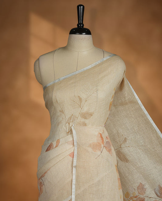 Beige colour pure linen saree featuring leaf print pattern across body, silver thin border finished with matching blouse.