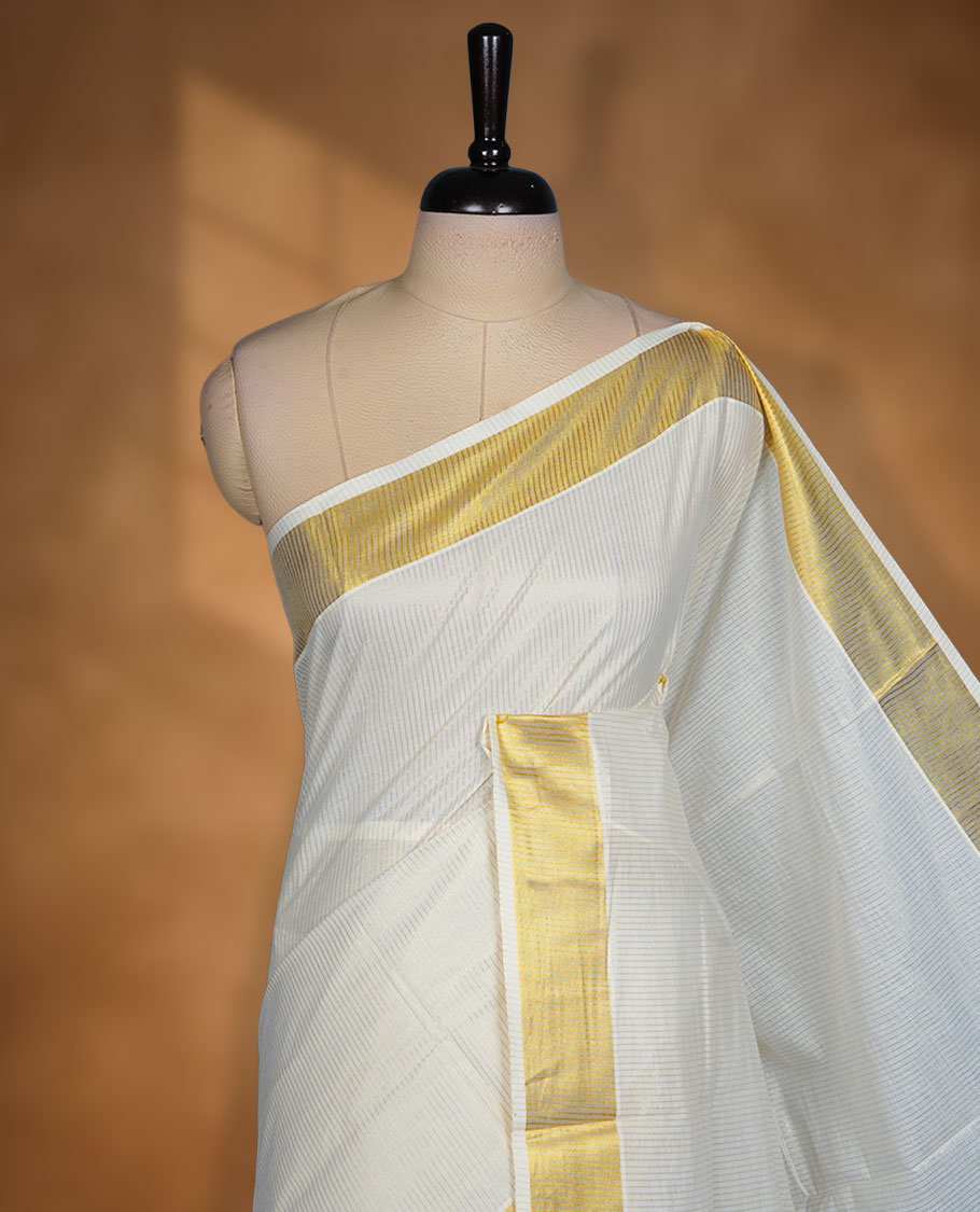 Off white colour Kerala cotton saree featuring fine golden stripes, complemented by a classic zari border and traditional pallu, paired with a matching blouse.