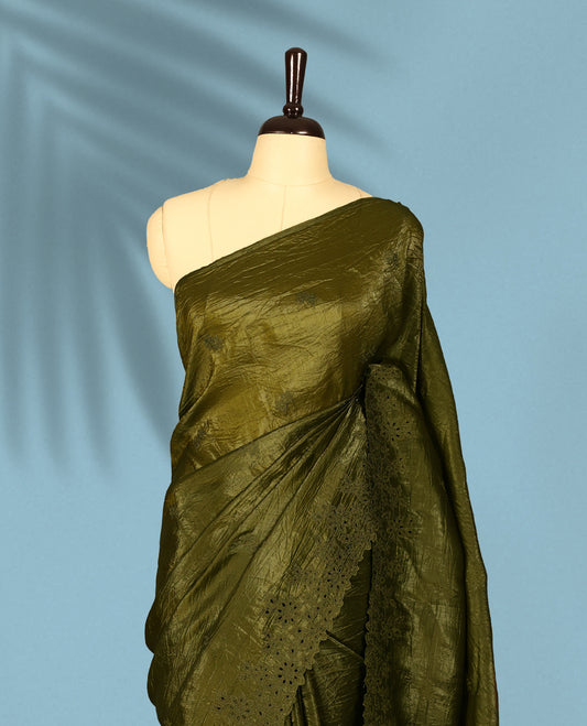 Olive Colour crush soft silk saree boasts a lustrous crinkled texture with subtle self colored floral Motifs on the body and an elegant Floral thread cutwork border, paired with a matching blouse.