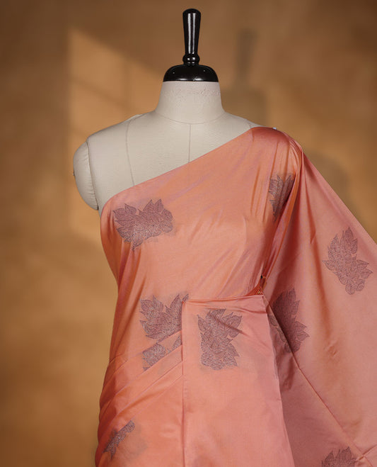 Dark peach colour semi soft silk saree adorned with delicate woven floral motifs on the body, complemented by a contrast red colour woven pallu with intricate detailing and tassel accents without border & Comes with a matching blouse piece.