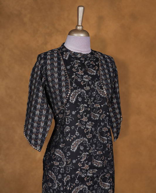 Black colour printed kurti by Talisha with all‑over paisley motifs, attached chevron shrug‑style layer, straight calf‑length silhouette, round neckline, and elbow‑length sleeves.