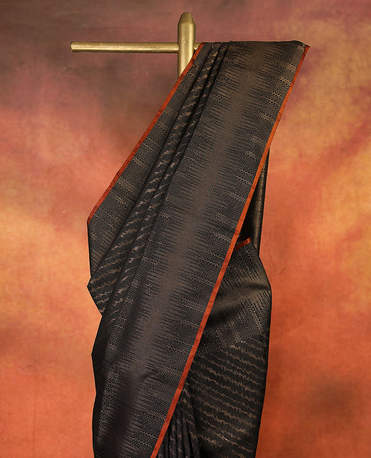 Deep black colour pure Mayuri silk saree featuring finely woven Golden zari motifs across the body, detailed with a subtle geometric self border with intricate texture, with matching blouse