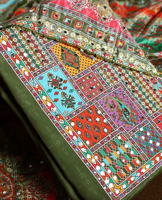 Elegant olive green churidhar material with vibrant multicolour geometric and paisley prints, enhanced with delicate mirror work, paired with a plain matching bottom and bold printed dupatta, perfect for festive occasions.