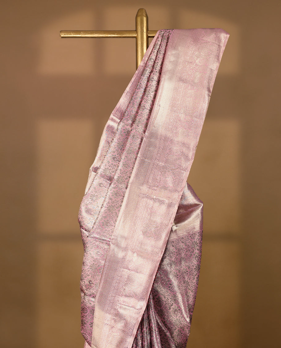 Pastel pink Colour Kancheepuram tissue silk saree adorned with intricate antique zari floral motifs on the body, beautifully complemented by traditional elephant and Chakkram design border, and paired with a matching blouse.