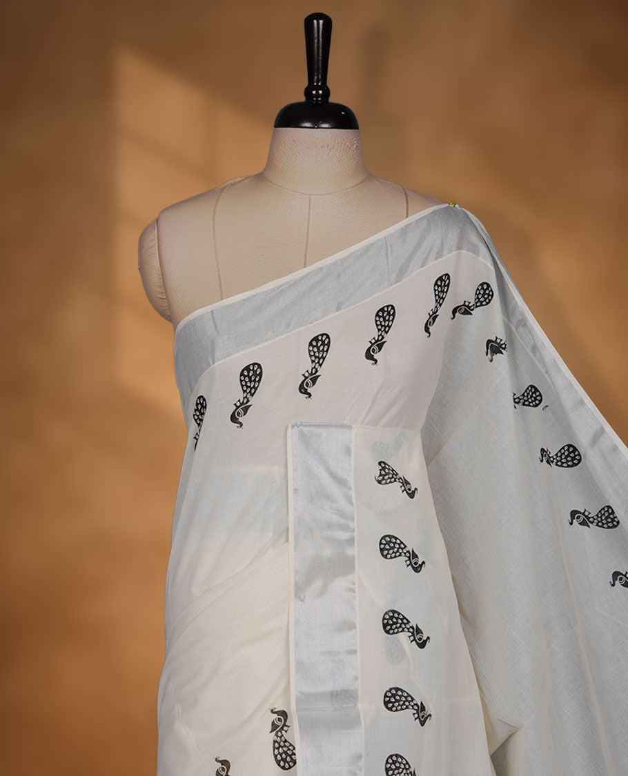 Off-white colour cotton Kerala saree featuring a subtle silver kasavu border, adorned with elegant black peacock motifs across the body and pallu, finished with a coordinated blouse for a refined, contemporary look.