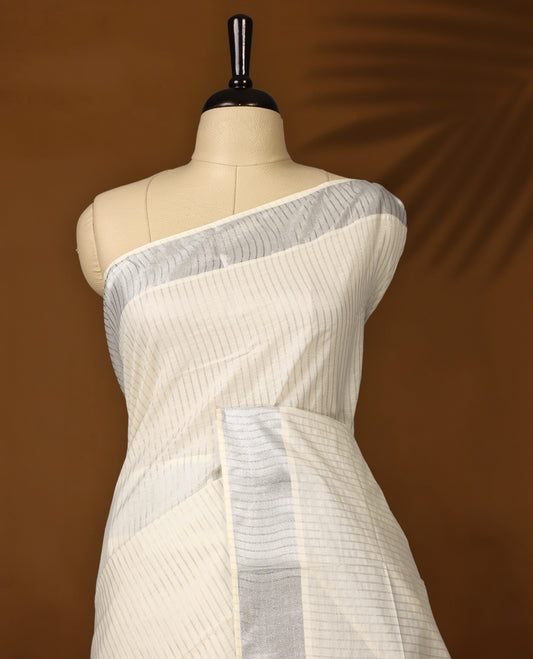 Elegant off white colour cotton Kerala saree featuring silver zari vertical stripes, sleek silver kasavu border & rich pallu, offering a timeless and graceful look and Pair with a matching blouse for festive elegance.