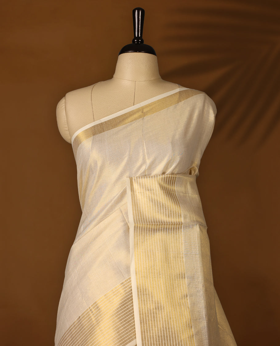 Elegant Light Gold colour Tissue Kerala saree featuring Plain body and traditional golden zari kasavu 5 Inch border  with White stripes offering a classic and graceful look, paired with a matching blouse.