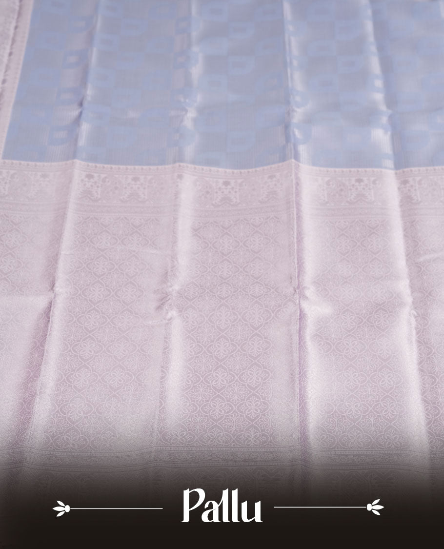Light lavender colour semi silk saree adorned with subtle silver zari motifs on the body, complemented by a pastel light blue pallu intricately woven with rich floral patterns border and pallu, and paired with a matching blouse