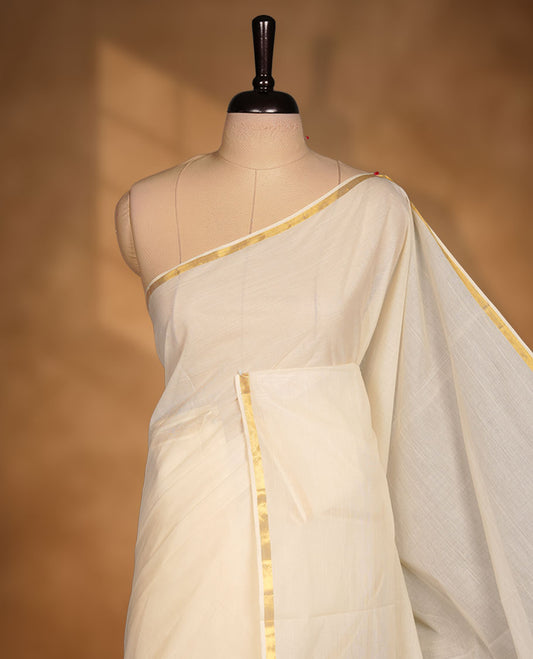 Off-white colour cotton Kerala saree with a subtle gold kasavu border, featuring a clean, plain body and airy texture, paired with a matching blouse.