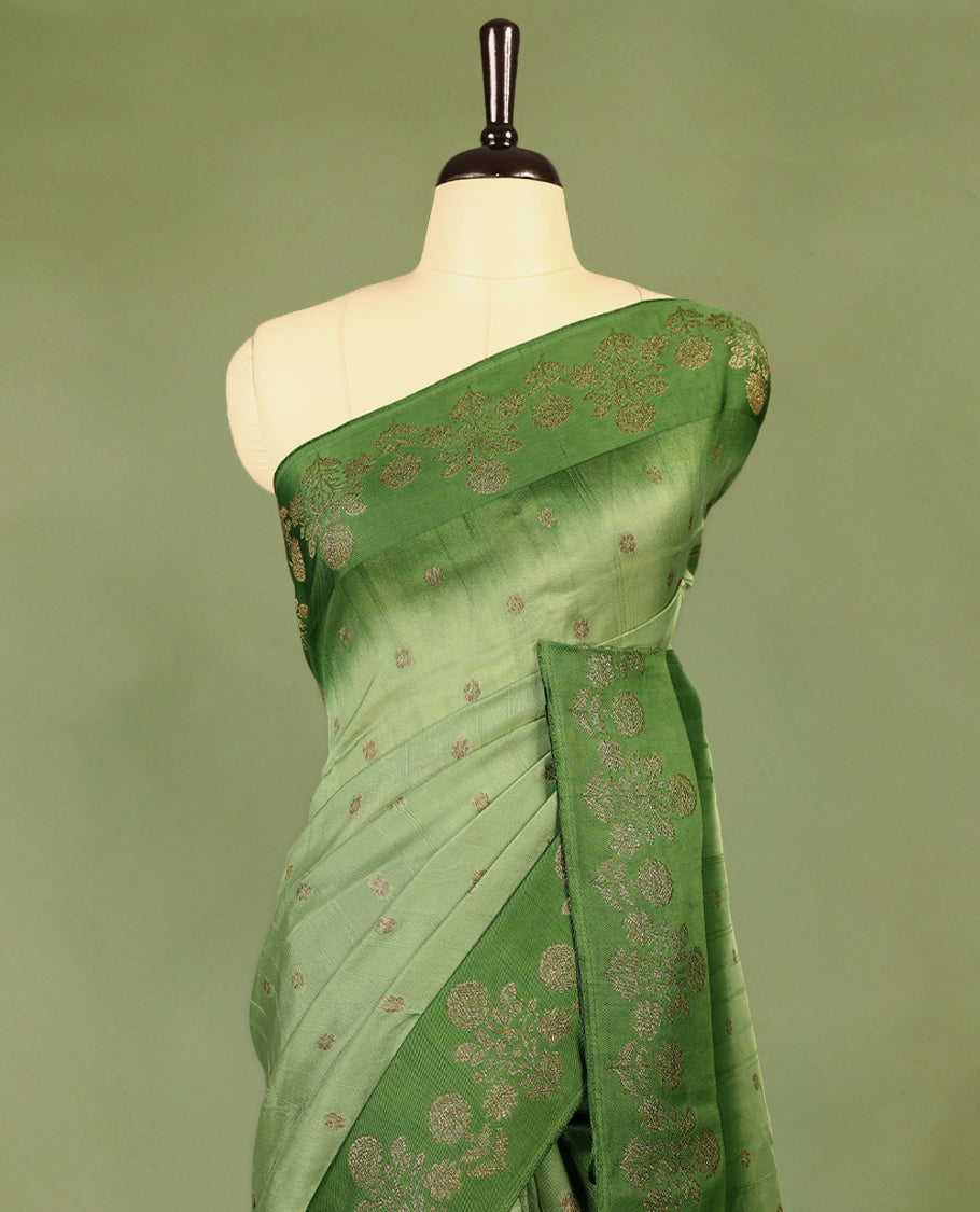 Green double shade semi Banaras Tussar Georgette saree adorned with elegant antique gold zari floral motifs across the body, featuring a detailed woven border and grand pallu, paired with a matching blouse piece.
