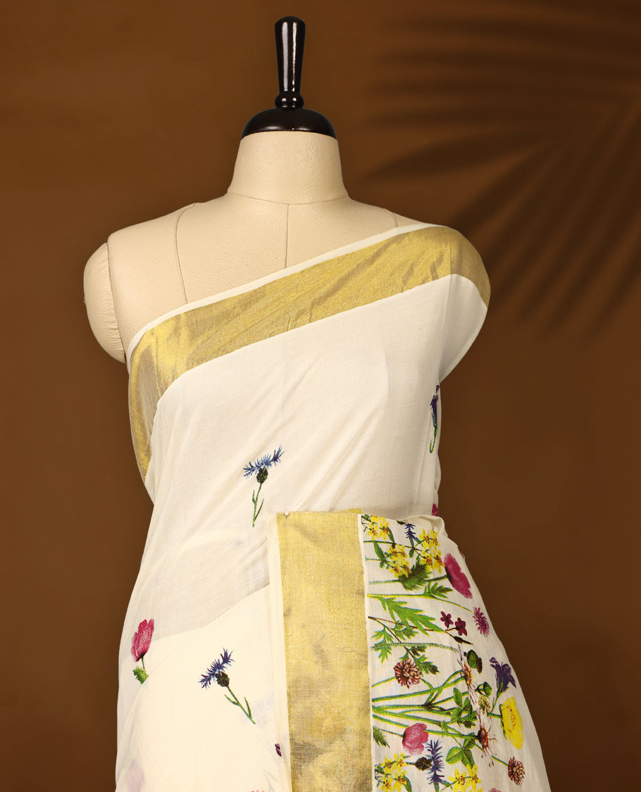 Elegant off white colour cotton Kerala saree with vibrant floral prints and a rich golden zari border, paired with a matching blouse. Perfect for festive occasions and day events with a graceful, natural charm.
